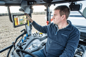 man inside the new holland cab using the technology screen